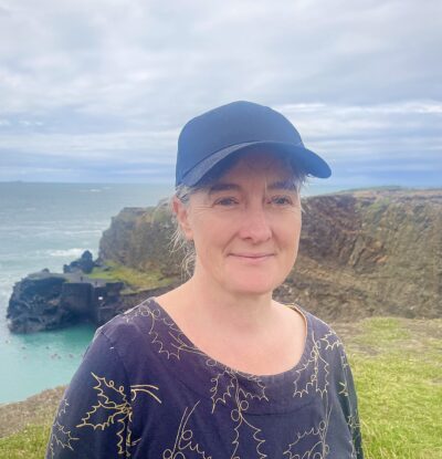 Woman with a baseball cap with a cliff and the sea in the background