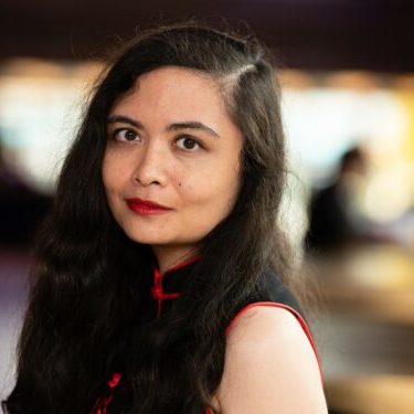 Head and shoulders headshot of a woman with long dark hair